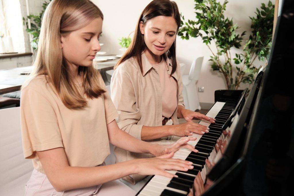 Mädchen bekommt Klavierunterricht von einer Lehrerin